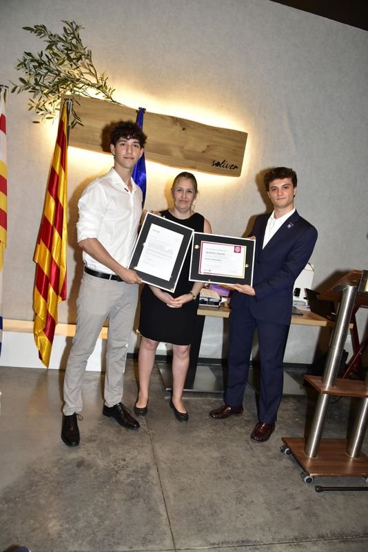 Dos socis de Rotaract Igualada sostenen el certificat de Rotary International del club, amb una dona al mig